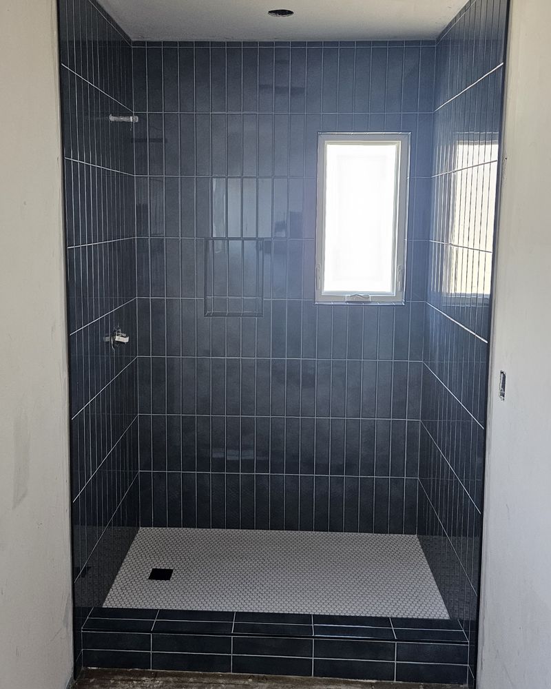 The same shower finished in vertical navy tile with a white mosaic floor