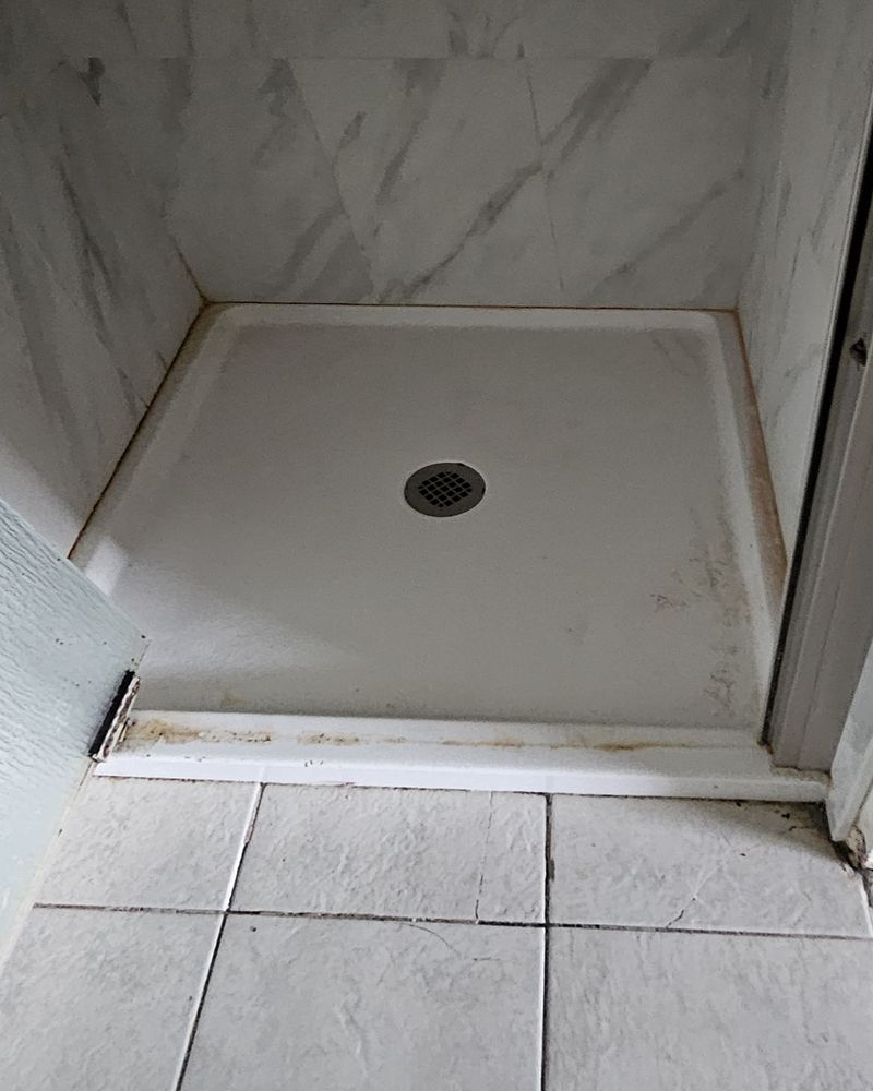 Shower stall with a stained fiberglass pan and a round drain