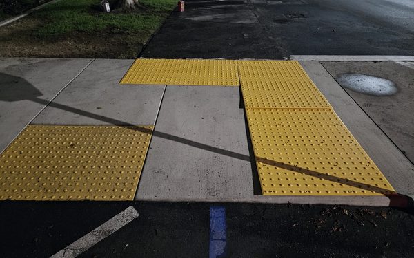 Re-poured concrete curb ramp with yellow detectable warning pads set into the walking surface