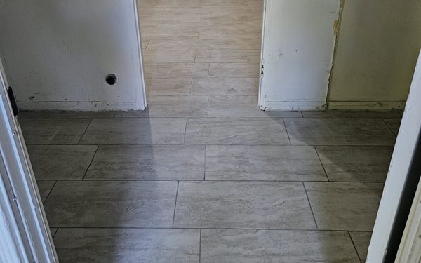 Hallway floored in gray plank tile running the length of the corridor, with the walls still unfinished