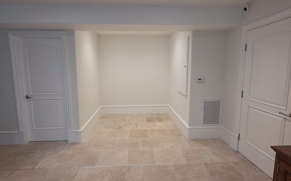 Alcove with a new travertine tile floor laid in a repeating pattern, fresh white baseboard, and painted doors either side