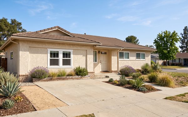 Design rendering of a stucco house front where the old garage opening is filled in with matching stucco and two windows, and the driveway is shortened with planting