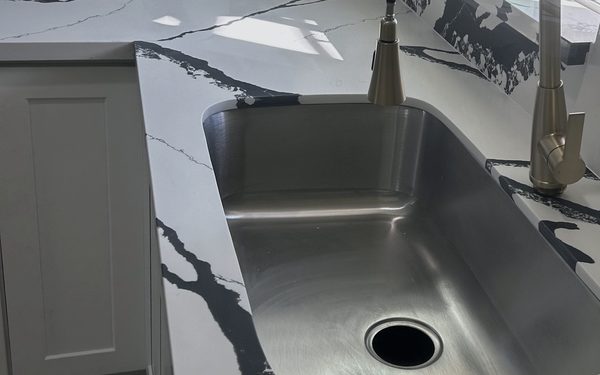 Close view of a black veined white quartz countertop with an undermount stainless steel sink and a brushed nickel faucet