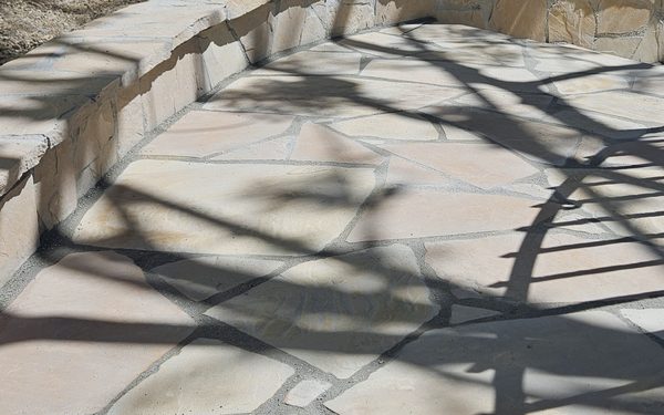 Flagstone paving with tight mortared joints running up to a low curved stone seat wall
