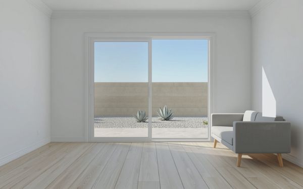 Design rendering of a white family room with a closed two panel sliding glass patio door looking out on a concrete patio, agave and a tan block wall, and a light gray sofa beside the side wall